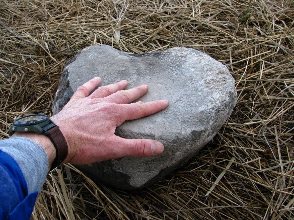 a hand touching the bowl of a grinding stone
