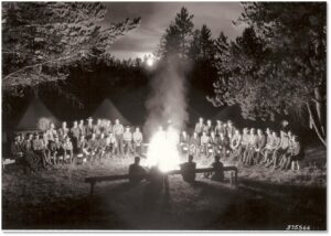People sitting around a campfire at night, photo in black and white