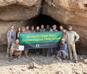 Northern Great Basin Arhcaeological Field School group holding a banner in front of Connely Caves